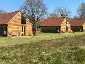 two wooden barns on a field next to a field at Nettlebed Farm Holiday Lets Barn3 in Durley