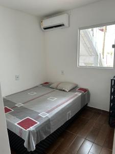 a bed in a white room with a window at dalton in Itacaré