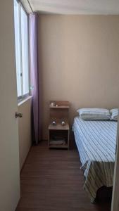 a bedroom with a bed and a nightstand next to a window at Apartamento en Piura - Perú in Piura