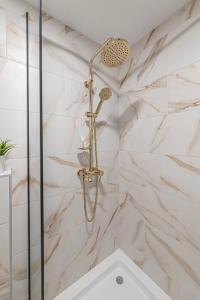 W łazience wyłożonej białym marmurem znajduje się prysznic. w obiekcie Luminious apartment with balcony by Polo Apartments w Kownie