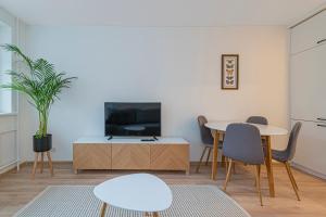 a living room with a tv and a table and chairs at Luminious apartment with balcony by Polo Apartments in Kaunas