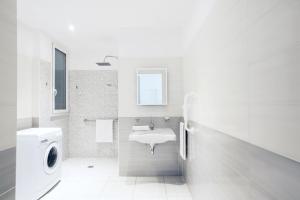 y baño blanco con lavabo y lavadora. en Vuelle Residence Apartments en Capo dʼOrlando