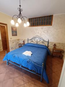 ein blaues Bett in einem Schlafzimmer mit einem Kronleuchter in der Unterkunft Abbentu in Zafferana Etnea