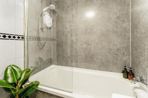 a bathroom with a white tub and a shower at Spacious 2-Bedroom Main Door Apartment With Private Parking in Glasgow