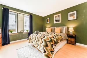 1 dormitorio con paredes verdes, 1 cama y ventana en Spacious 2-Bedroom Main Door Apartment With Private Parking en Glasgow