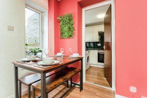 a dining room with a table and a pink wall at Spacious 2-Bedroom Main Door Apartment With Private Parking in Glasgow