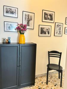 un armario negro con un jarrón de flores y una silla en Casa Cinque apartment in Pompei, en Pompeya