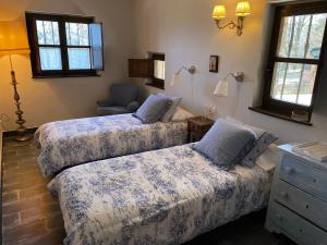 a bedroom with two beds and a chair and windows at LA QUINTA DE PUELLES in Ambás