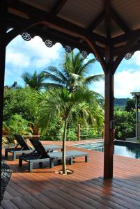 a porch with chairs and a palm tree next to a pool at Villa Mamalouken : App Léonie in Rivière-Pilote