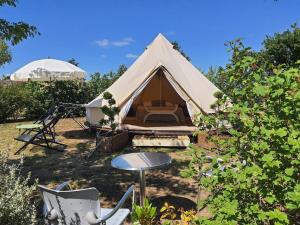 アルゾンヌにあるL'Escale Occitaneの庭にテーブルと椅子が備わるテント