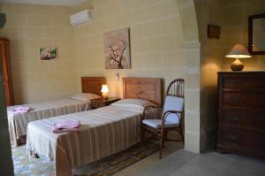 Cette chambre comprend deux lits, une chaise et une commode. dans l'établissement Jenkins Holiday Farmhouse, à L-Għarb