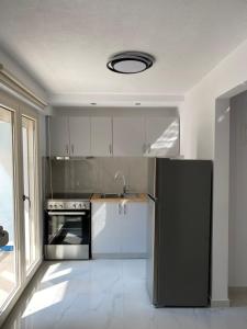 a kitchen with a black refrigerator and a sink at White Apartment in Kavala