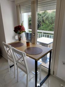 a dining room table with two chairs and a window at White Apartment in Kavála