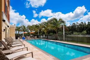 a swimming pool with lounge chairs and palm trees at TownePlace Suites by Marriott Fort Myers Estero in Estero