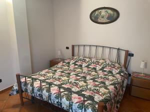 a bed with a floral comforter in a bedroom at Casa Gatti: villa con giardino con accesso indipendente in Rivanazzano