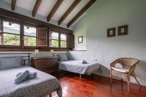 a room with two beds and a chair and windows at L´Agüera de Soberron in Llanes