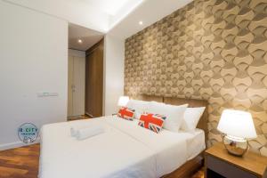 a bedroom with a large white bed and a wall at Grand Medini Suites by JBcity Home in Nusajaya