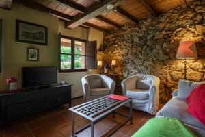 a living room with a couch and chairs and a tv at L´Agüera de Soberron in Llanes