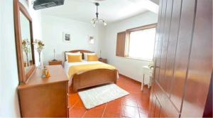 una camera da letto con un letto con lenzuola gialle e uno specchio di Lugar do Sonho Guest House a Cercal