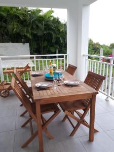 une table et des chaises en bois sur un porche dans l'établissement L'albizia, à Les Anses-d'Arlet