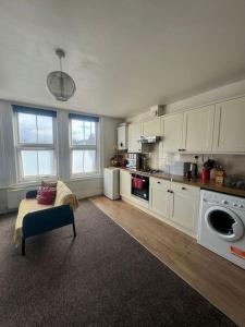 a kitchen with white cabinets and a couch in a room at Comfy entire place for max 4. in London