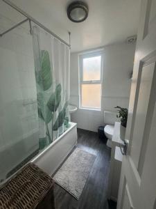 a bathroom with a shower and a toilet and a window at Comfy entire place for max 4. in London