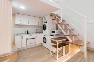 a kitchen with white cabinets and a spiral staircase at Apartamento lujoso cercano al centro de Madrid in Madrid