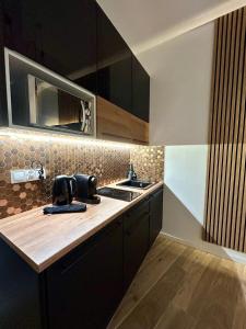 a kitchen with black cabinets and a wooden counter top at Ocean Black jacuzzi in Kraków