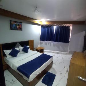 1 dormitorio con cama con sábanas azules y ventana en HOTEL SHREE RADHE, en Ahmedabad