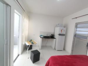 a white kitchen with a refrigerator and a table at Inovally in Guarulhos