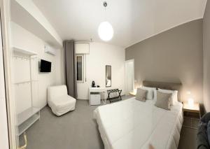 a white bedroom with a large white bed and a chair at 4Th Floor Caserta in Caserta