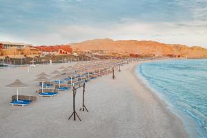 una playa con sombrillas y sillas y el océano en Pickalbatros Vita Resort - Portofino Marsa Alam en Abu Dabab