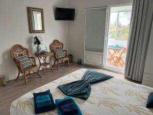 a bedroom with a bed and chairs and a balcony at Caloura Water Accommodation in Lagoa
