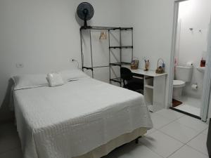 a bedroom with a bed and a desk and a bathroom at Inovally in Guarulhos