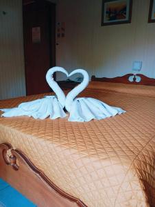 Dos cisnes haciendo un corazón en una cama en Apart Hotel Géminis, en Termas del Daymán