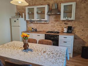 a kitchen with a table with a vase of flowers on it at Šimun&Jakov in Drinovci