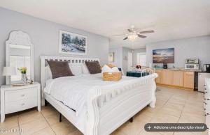 a bedroom with a large white bed and a kitchen at Tomoka River Guest House in Ormond Beach