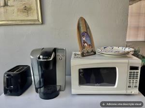 a microwave sitting next to a toaster and a coffee maker at Tomoka River Guest House in Ormond Beach