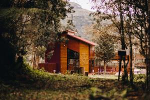 a small wooden building with a mountain in the background at Chalé Aconchego - Pousada Cachoeira da Neve in Urubici