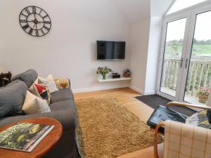 sala de estar con sofá y reloj en la pared en The Loft at Lucott House, en Bath