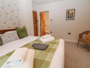 a bedroom with a bed with a green blanket and a chair at The Loft at Lucott House in Bath