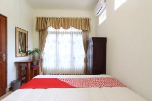 um quarto com uma cama com um cobertor vermelho em OYO 93789 Mbah Carik Homestay em Magelang