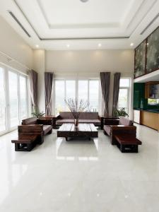 een grote woonkamer met banken, tafels en ramen bij Homestay Hạ Long VIP in Ha Long