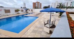a swimming pool with a blue umbrella and chairs at Belíssimo apartamento a 01 km da litorânea in São Luís