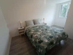 a bedroom with a bed with a green comforter at Aux 2 Rivières in Saint-Léger-de-Peyre