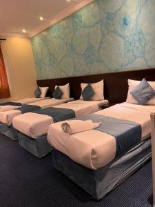 a group of four beds in a room at EWG Mahbas Hotel in Mecca