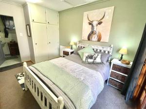 a bedroom with a bed with a deer picture on the wall at The Hedge at Dullstroom Cottage in Dullstroom