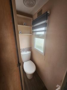 a small bathroom with a toilet and a window at Kingfisher OAK 1098 Dees Caravan Lettings in Ingoldmells