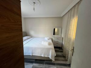 a bedroom with a white bed and a dresser at Duranapart Fethiye in Fethiye