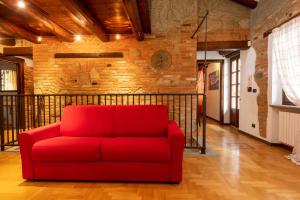- un canapé rouge dans une pièce dotée d'un mur en briques dans l'établissement Peiragal, à La Morra